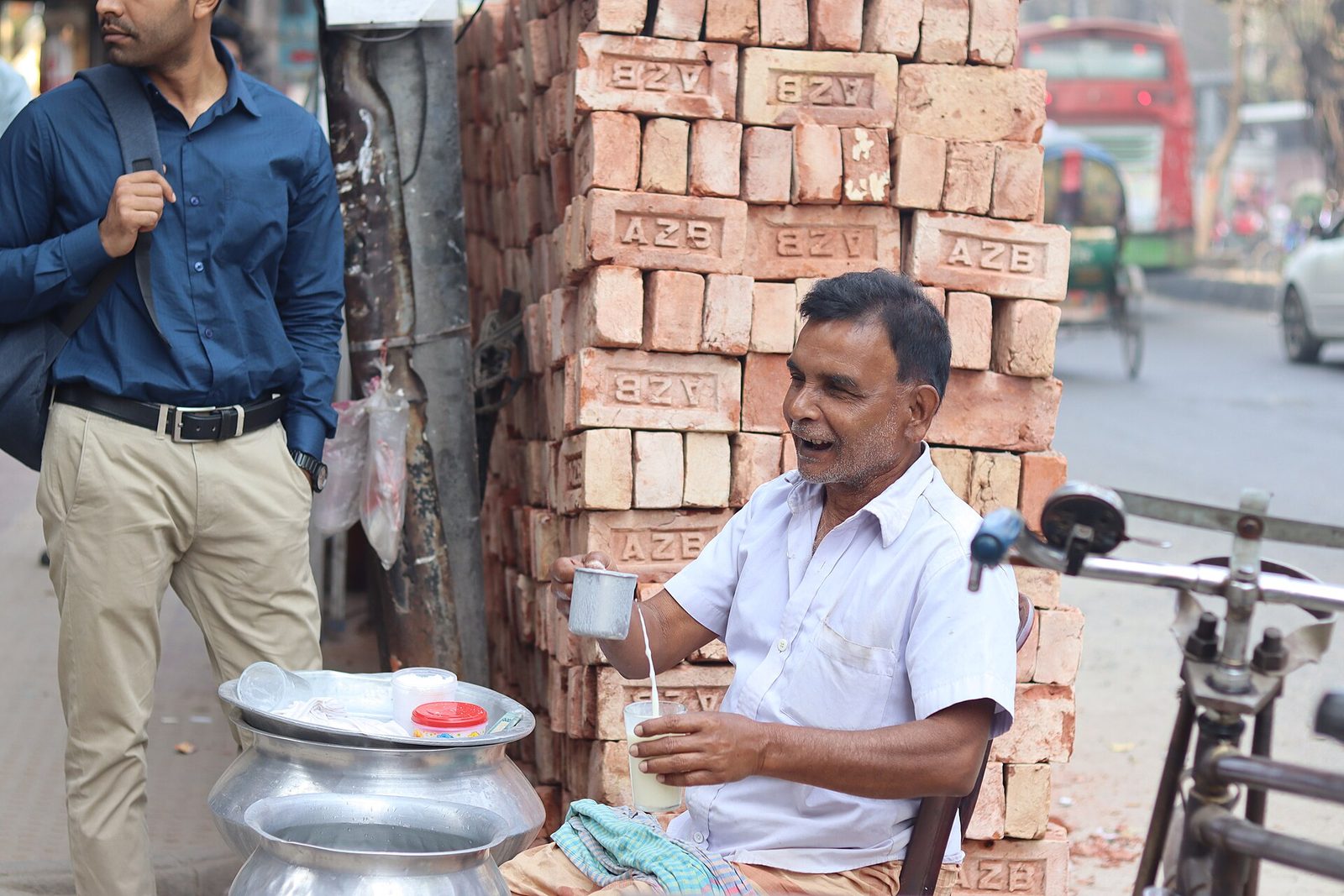 A street food seller serves a drink beside a stack of bricks in Dhaka. A file photo, not connected to the new licensing notice.